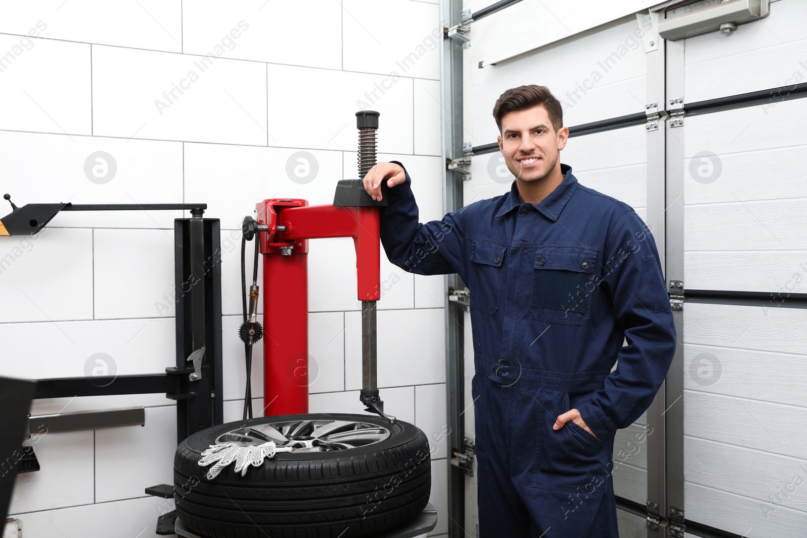 Photo of Man near tire fitting machine at car service