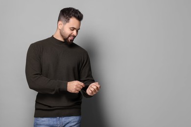 Handsome man in stylish sweater on grey background, space for text