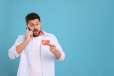 Photo of Emotional man with credit card talking on smartphone against light blue background, space for text. Be careful - fraud