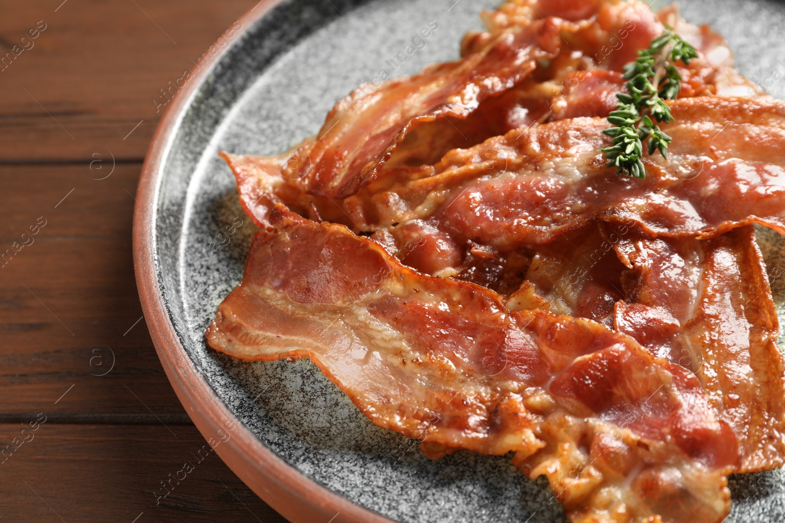 Photo of Plate with fried bacon on wooden background