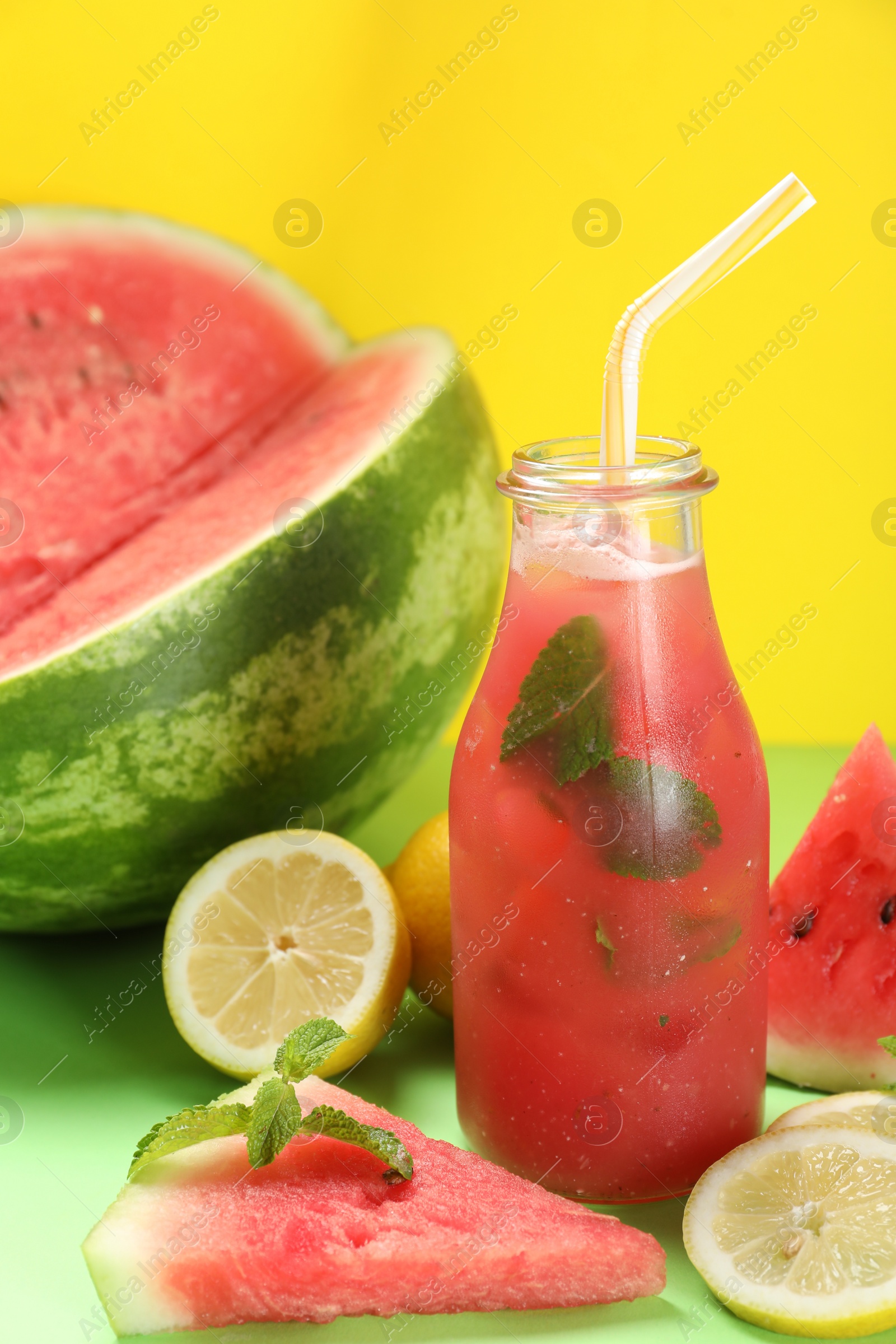 Photo of Tasty watermelon drink and fresh fruits on green table against yellow background