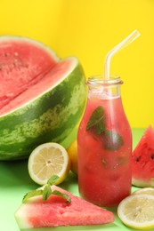 Tasty watermelon drink and fresh fruits on green table against yellow background