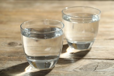 Glasses of water on wooden table, space for text. Refreshing drink