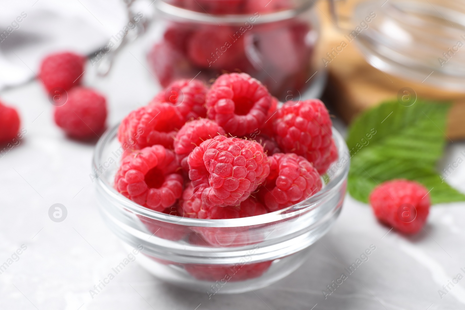 Photo of Delicious fresh ripe raspberries on light grey table, closeup