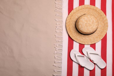 Photo of Beach towel, hat and flip flops on sand, flat lay. Space for text