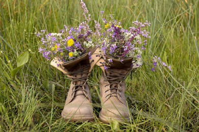 Photo of Boots with beautiful wild flowers on grass
