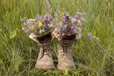 Boots with beautiful wild flowers on grass