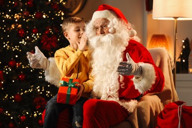 Photo of Merry Christmas. Little boy whispering his wish to Santa at home