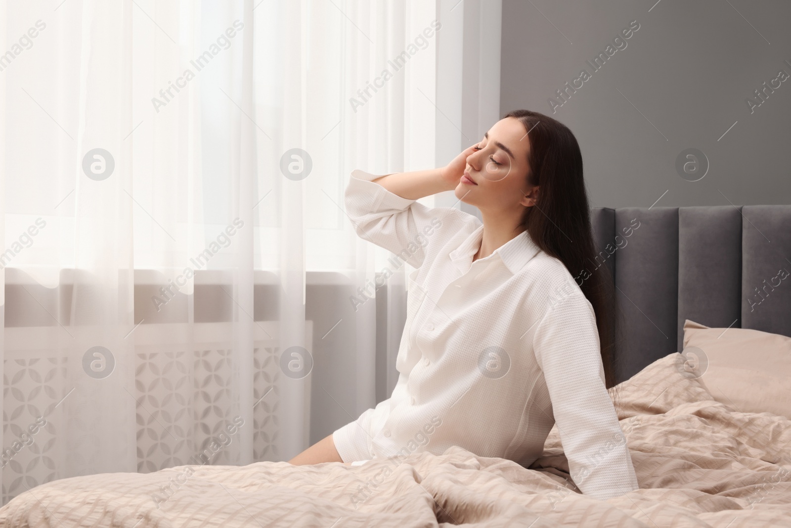 Photo of Beautiful woman sitting on bed at home, space for text. Lazy morning