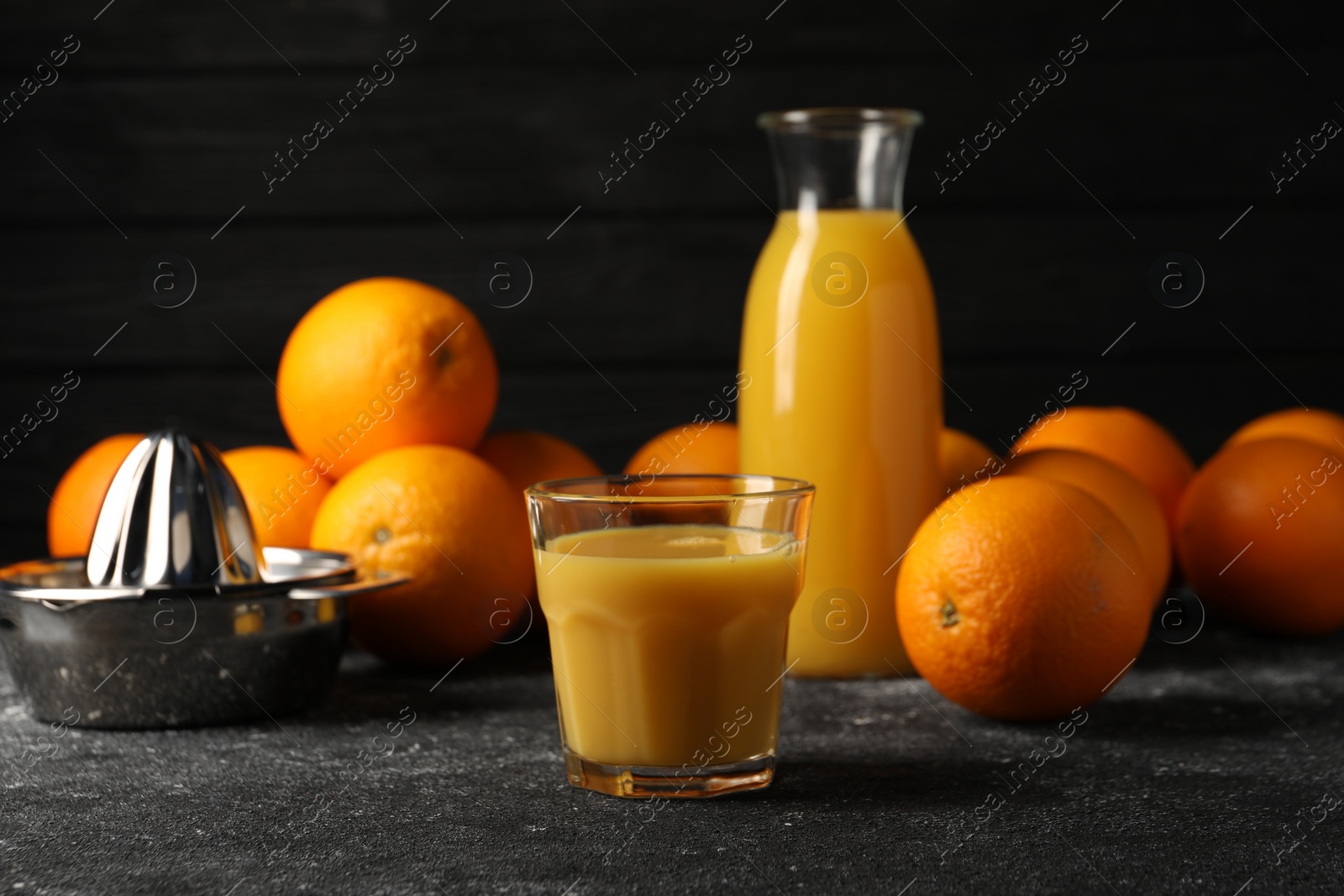 Photo of Tasty fresh oranges and juice on black table