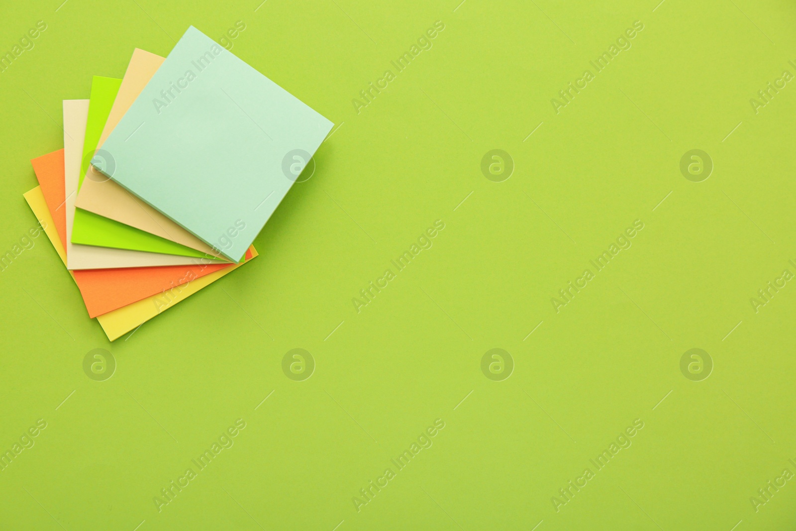 Photo of Stack of colorful stickers on light green background, top view. Space for text