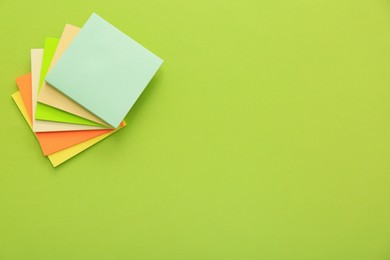 Stack of colorful stickers on light green background, top view. Space for text