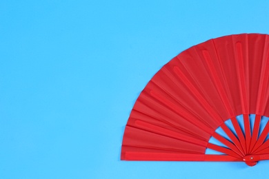 Photo of Red hand fan on light blue background, top view. Space for text