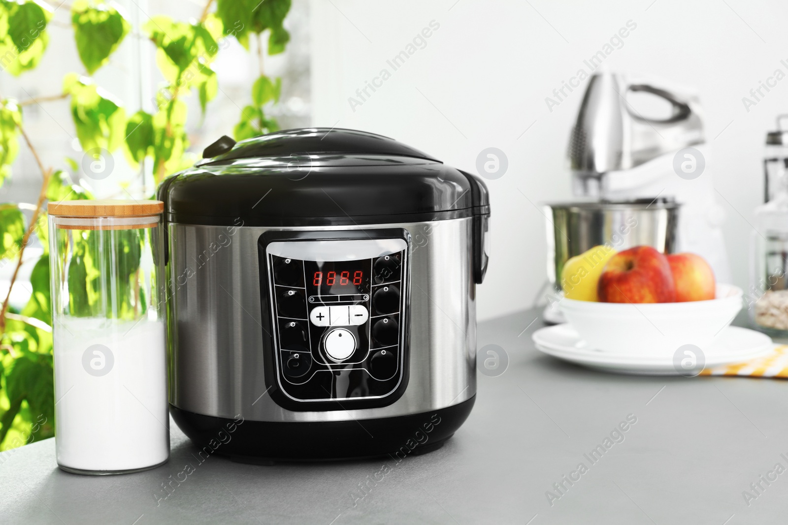 Photo of New modern multi cooker and jar of flour on table in kitchen. Space for text