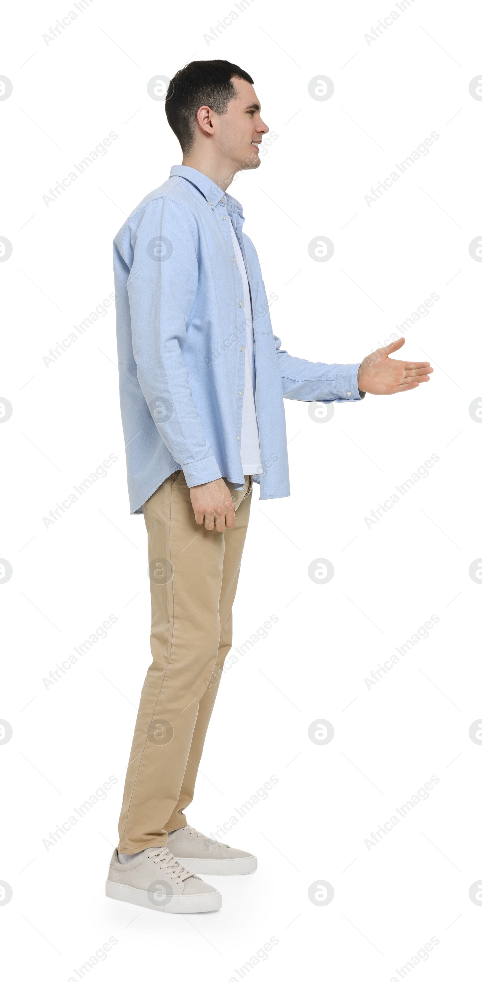 Photo of Young man in light blue shirt and beige pants on white background