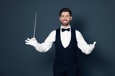 Happy professional conductor with baton on grey background