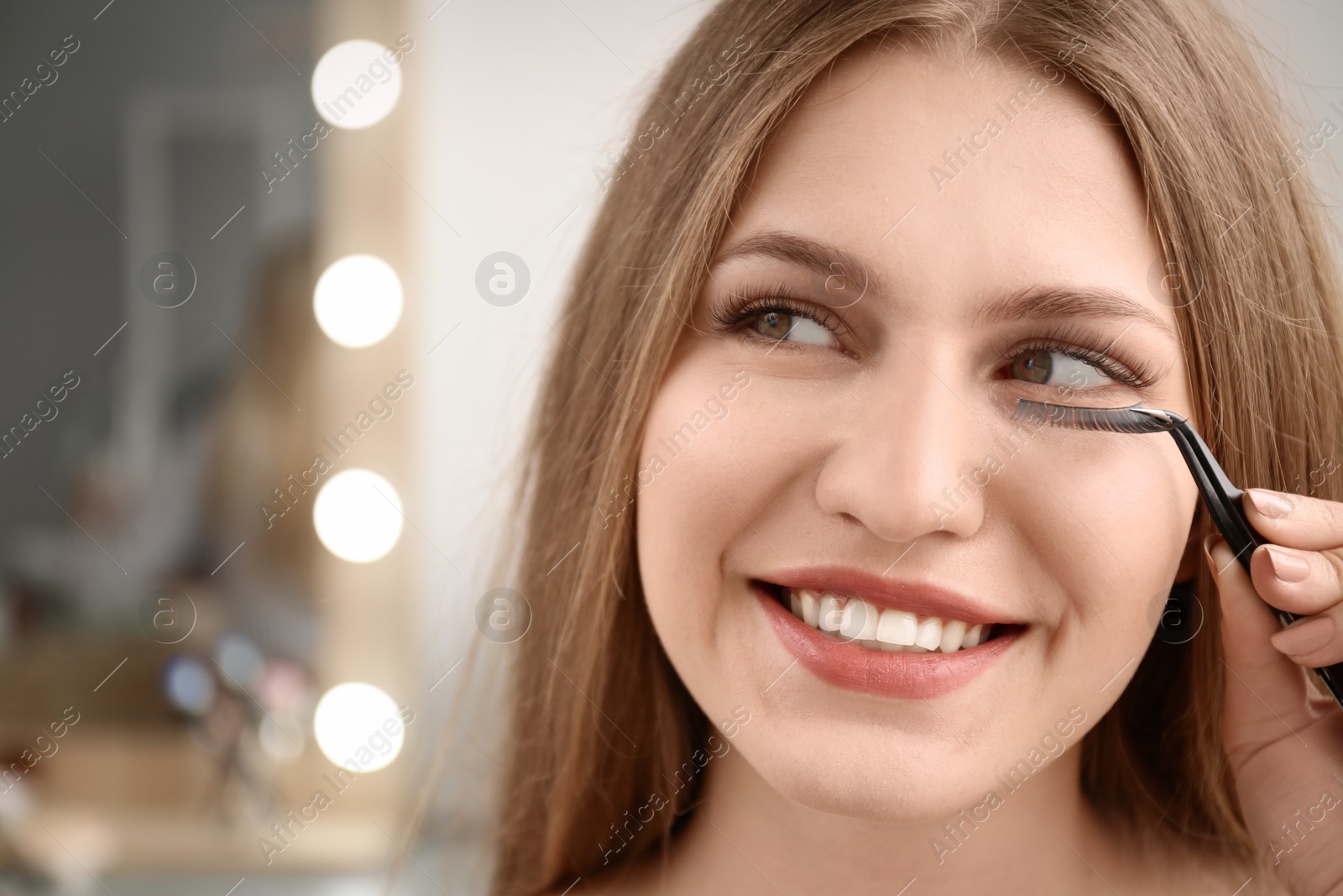 Photo of Attractive young woman with false eyelashes on blurred background