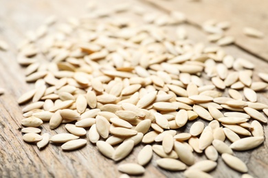 Photo of Raw cucumber seeds on wooden background, closeup. Vegetable planting