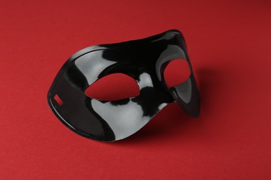 Photo of Black theatre mask on red background, closeup
