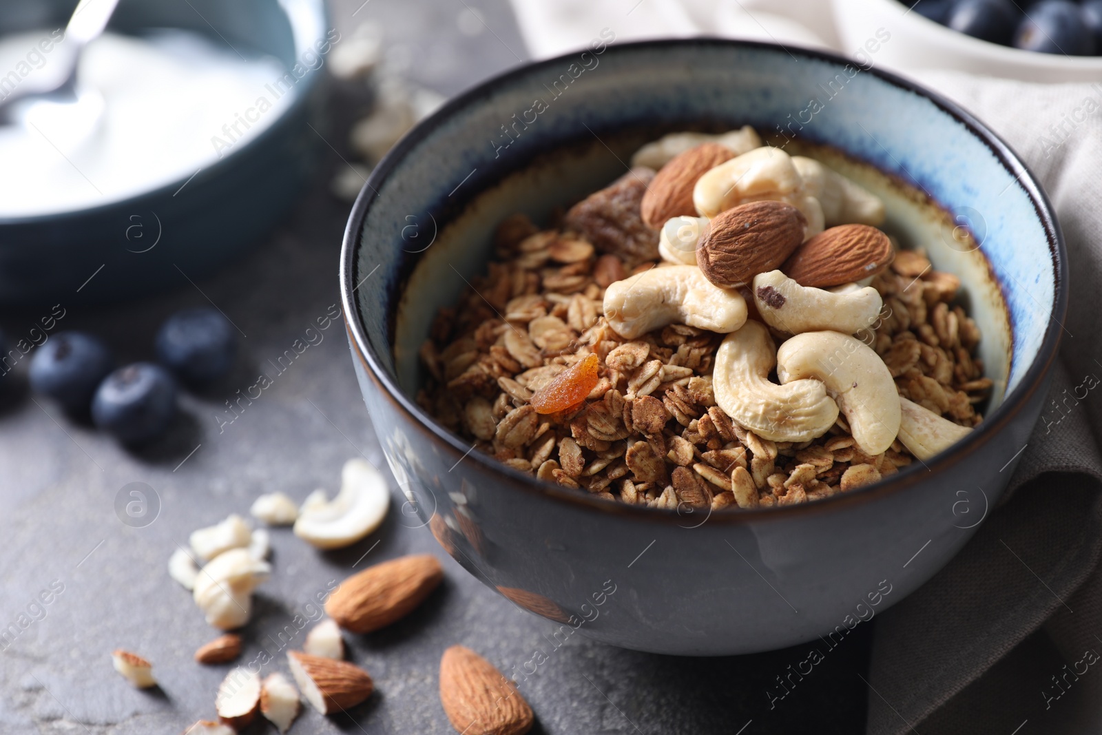 Photo of Tasty granola with nuts in bowl on gray table, closeup