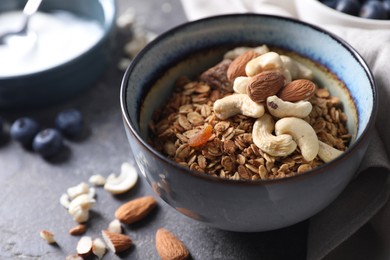 Photo of Tasty granola with nuts in bowl on gray table, closeup