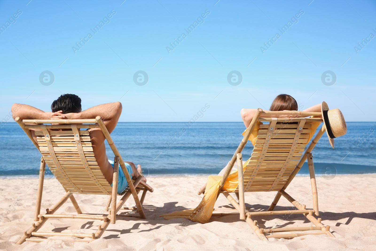 Photo of Woman and her boyfriend on deck chairs at beach. Lovely couple