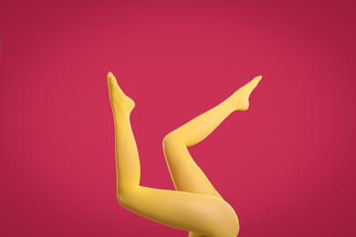 Photo of Woman wearing yellow tights on crimson background, closeup of legs