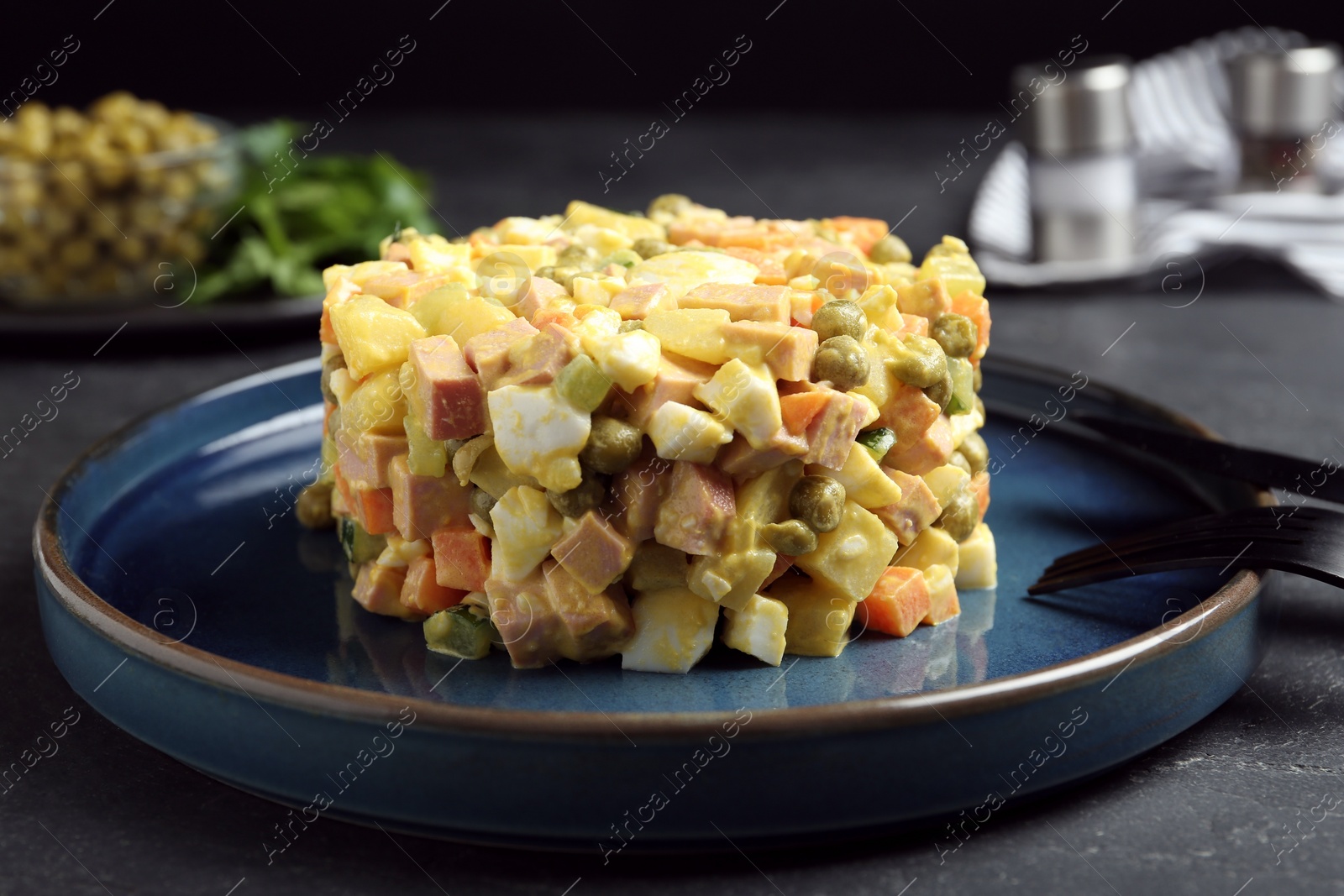 Photo of Delicious russian salad Olivier served on black table