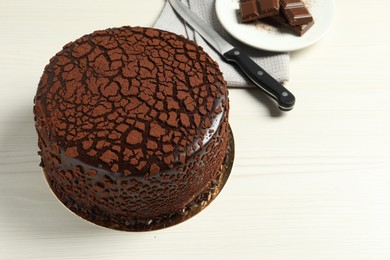 Delicious chocolate truffle cake and knife on light wooden table, space for text