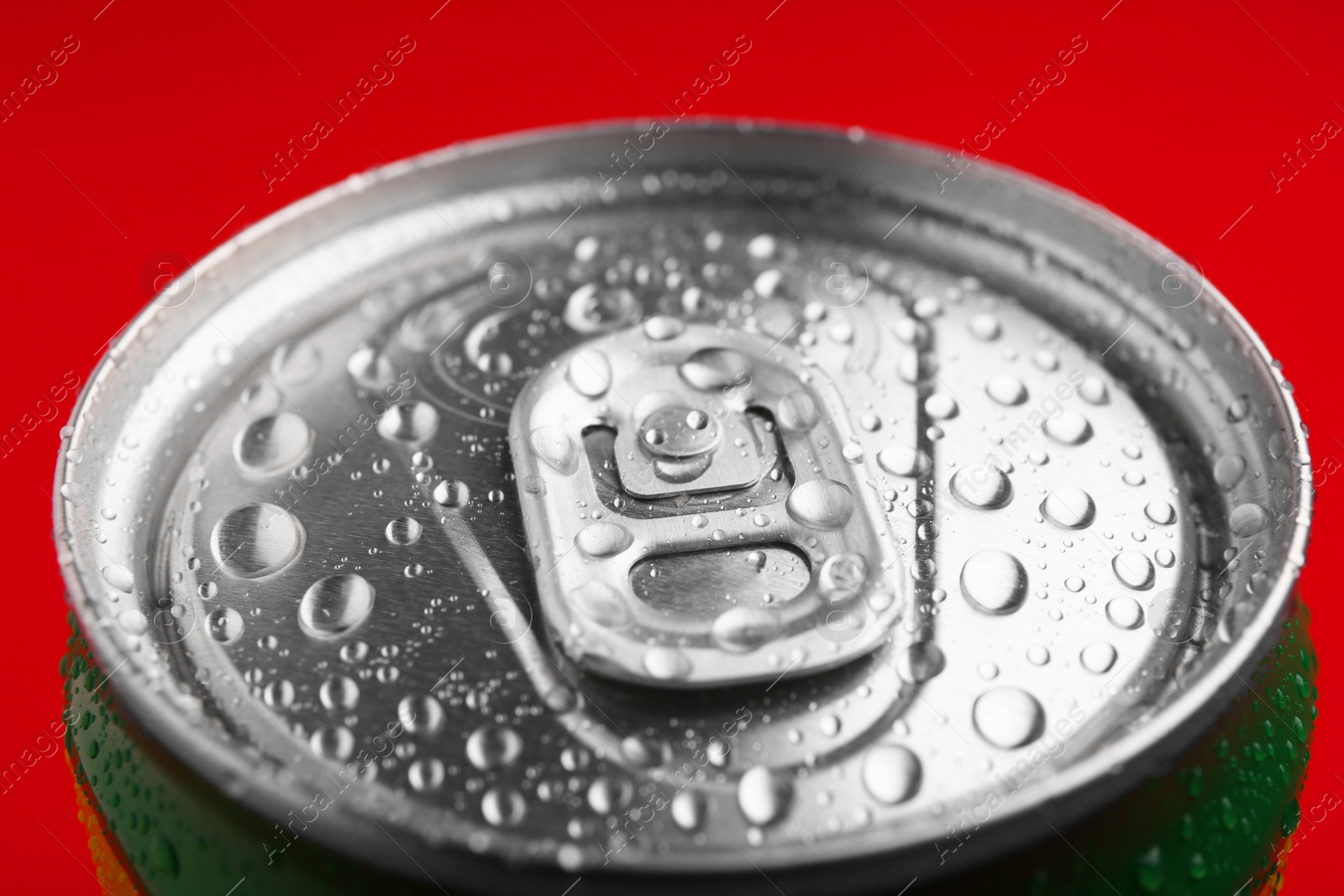 Photo of Energy drink in wet can on red background, closeup