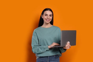 Happy woman with laptop on orange background