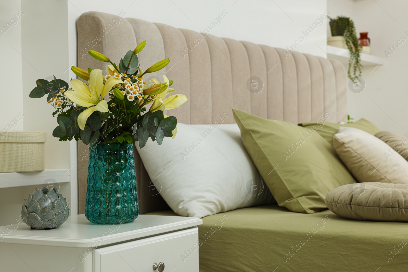 Photo of Bouquet of beautiful flowers and ceramic decor on nightstand in bedroom