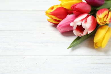 Photo of Beautiful spring tulips on white wooden table, closeup. Space for text