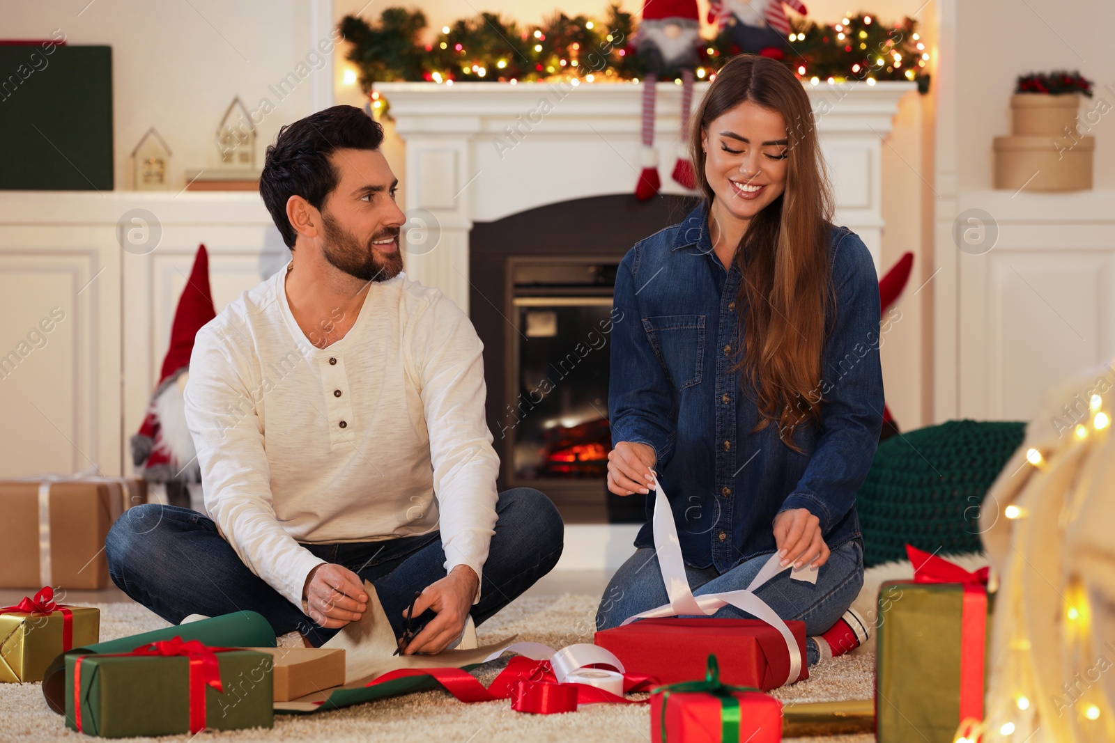 Photo of Happy couple decorating Christmas gifts at home