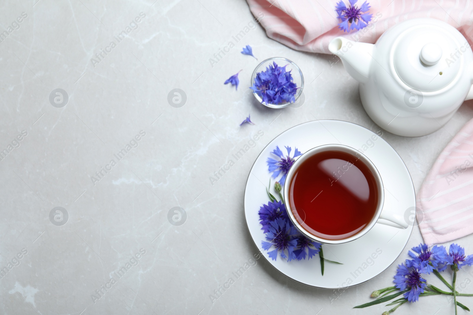 Photo of Composition with tea and cornflowers on light table, flat lay. Space for text