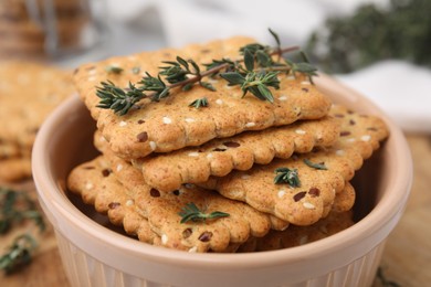 Photo of Cereal crackers with flax, sesame seeds and thyme in bowl on blurred background, closeup