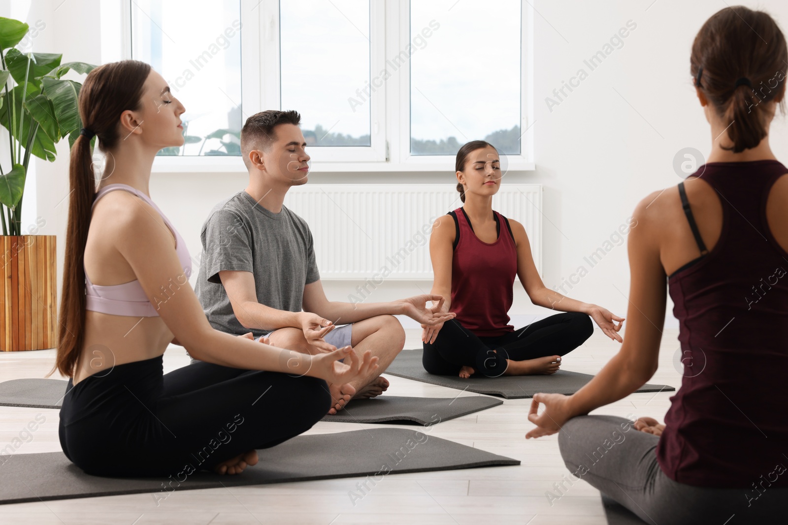 Photo of Group of people practicing yoga on mats indoors