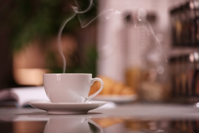 Photo of Cup of hot coffee on blurred background