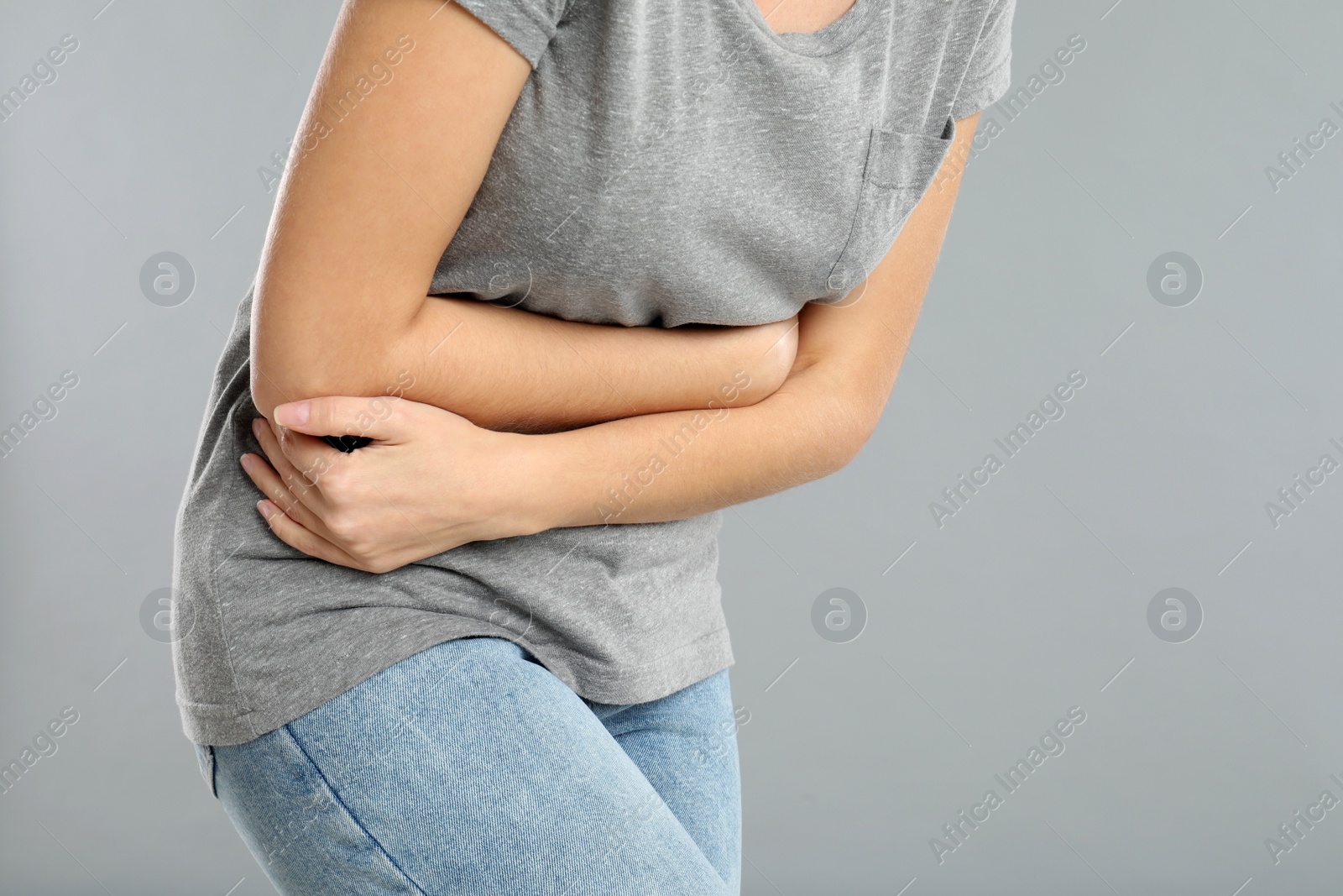 Photo of Closeup view of woman suffering from stomach ache on grey background, space for text. Food poisoning