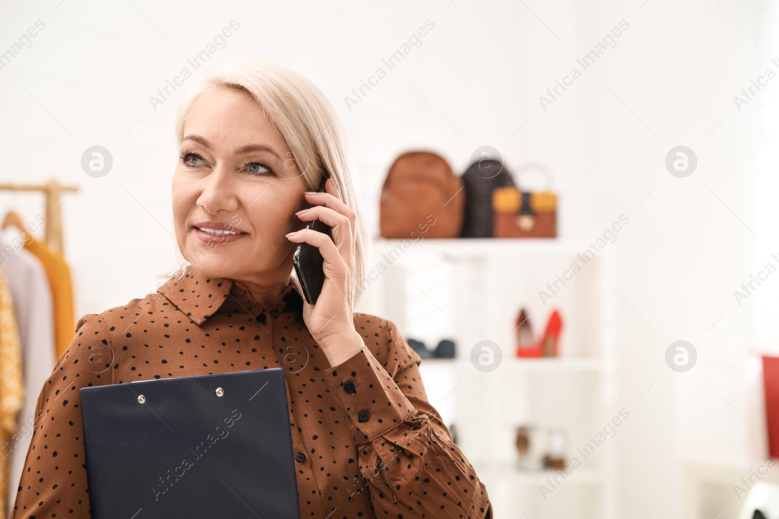 Photo of Female business owner talking on phone in boutique