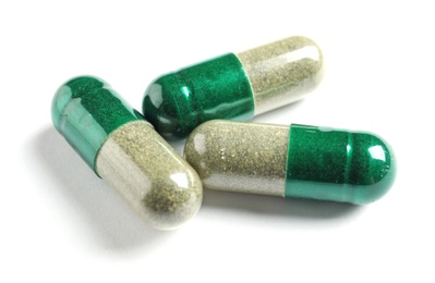 Photo of Green spirulina capsules on white background. Alternative medicine