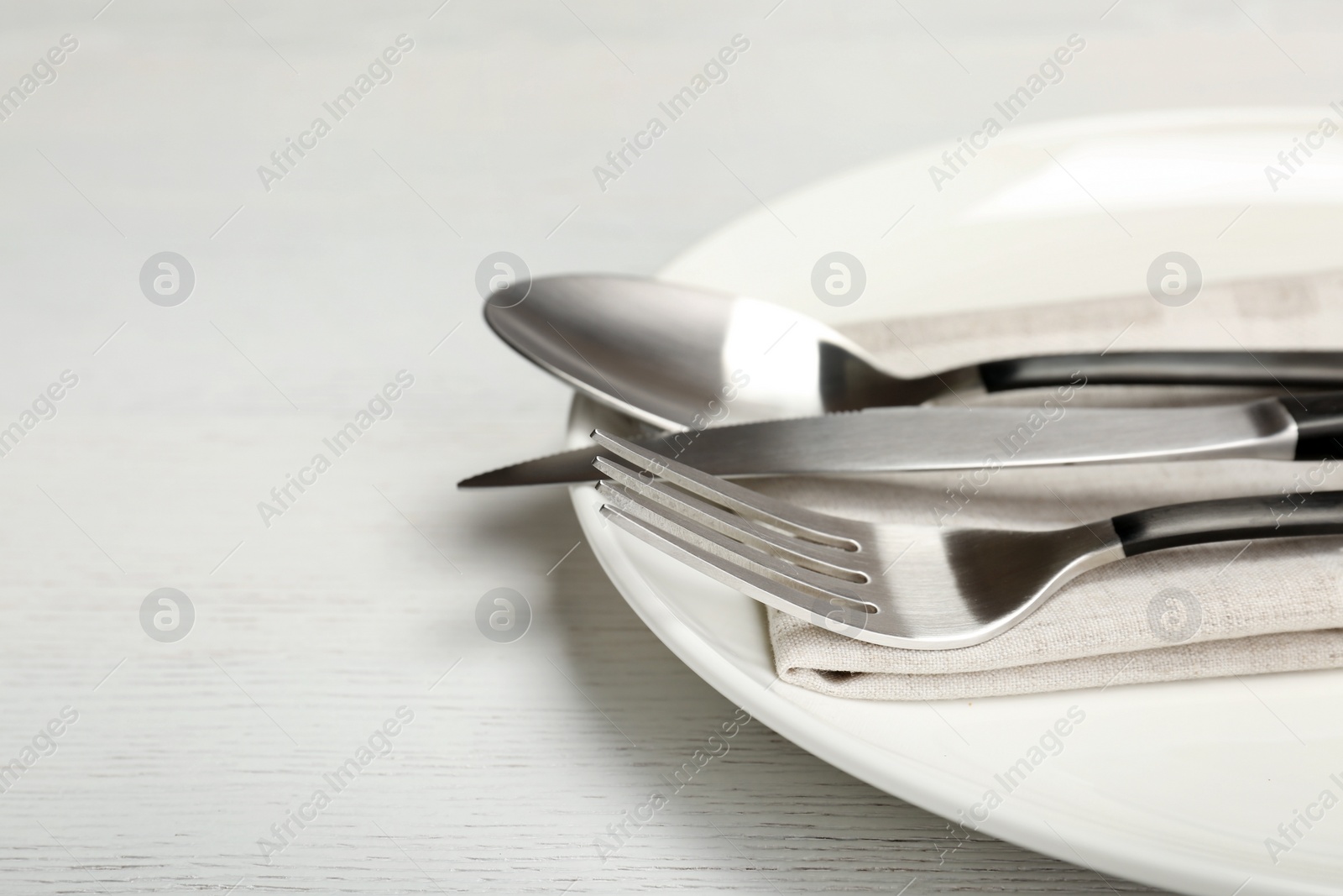 Photo of Plate with fork, knife and spoon on table, closeup. New setting