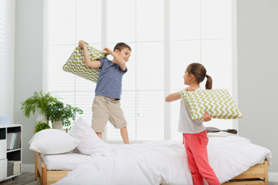 Photo of Happy children having pillow fight in bedroom