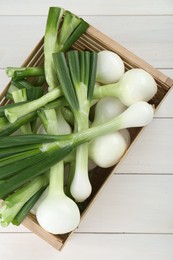 Photo of Crate with green spring onions on white wooden table, top view