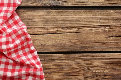 Photo of Checkered picnic tablecloth on wooden background, top view