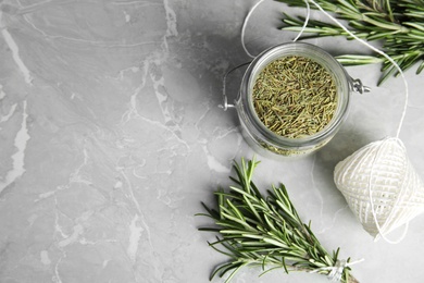 Photo of Flat lay composition with dried rosemary in jar and fresh twigs on grey table, space for text