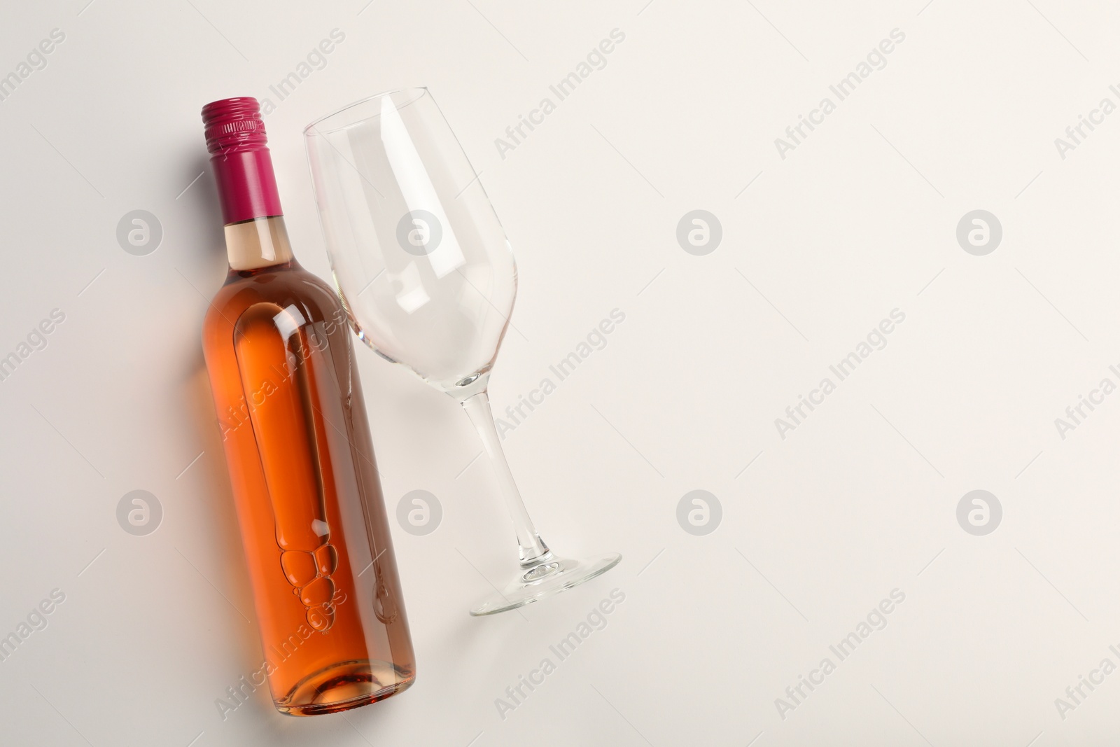 Photo of Bottle of expensive rose wine and wineglass on white background, top view. Space for text