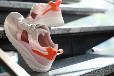 Pair of stylish women's sneakers on grey marble stairs indoors