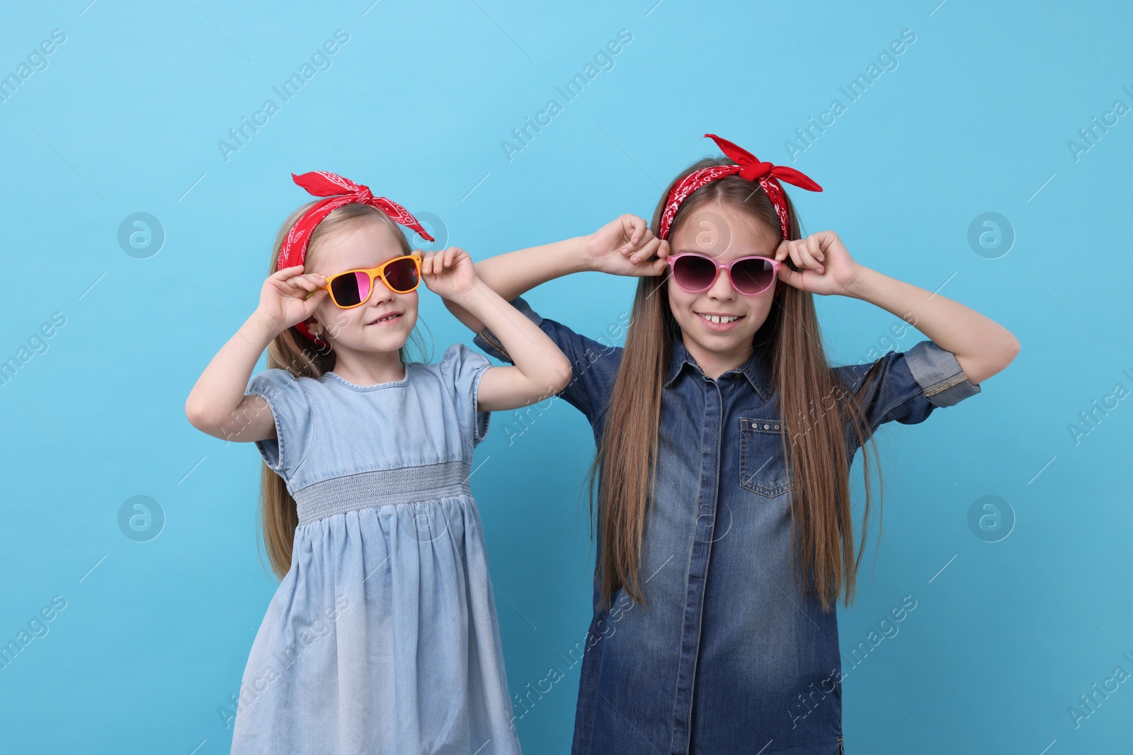 Photo of Cute little sisters on light blue background