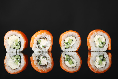 Delicious sushi rolls on black mirror surface